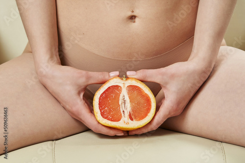 a beautiful slender female body and a cut half of a grapefruit between the legs. the concept of women's health, feminine hygiene, hair removal in the bikini area. photo