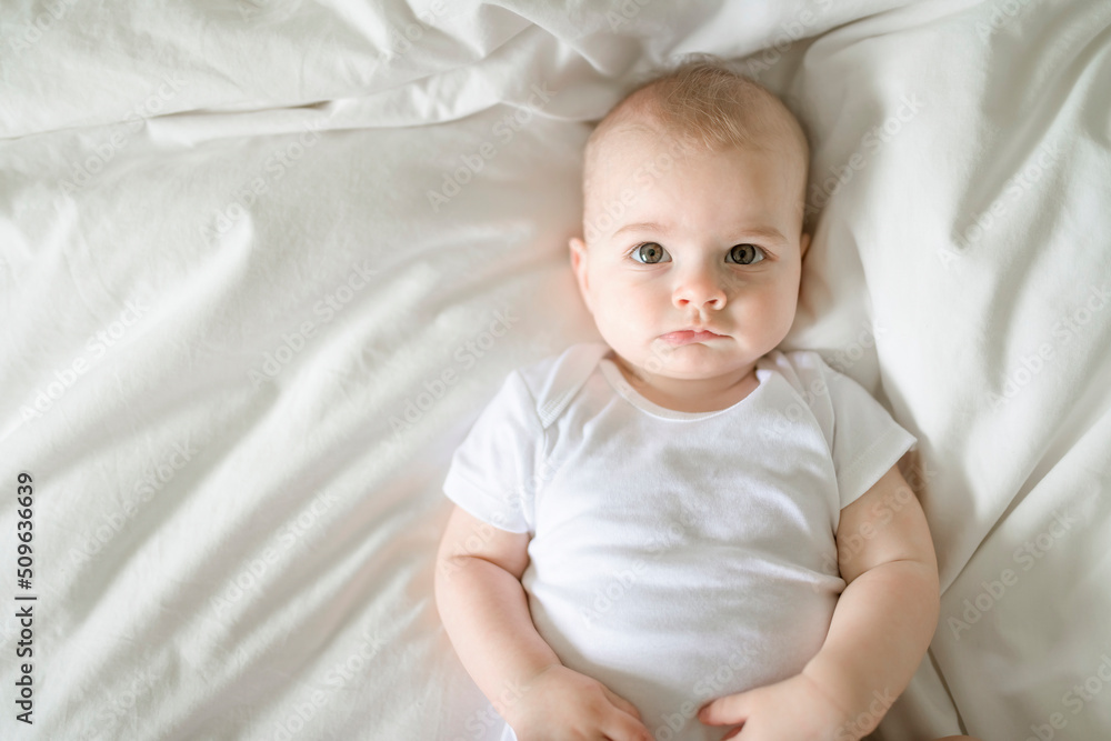 Adorable baby boy in white sunny bedroom in the morning at home Adorable baby boy in white sunny bedroom in the morning at home