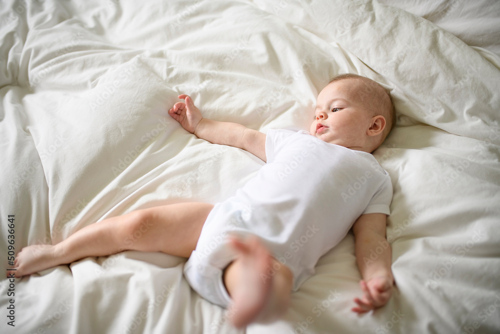 Adorable baby boy in white sunny bedroom in the morning at home Adorable baby boy in white sunny bedroom in the morning at home