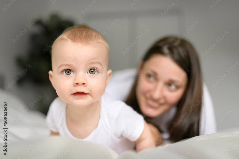 Mother and baby on white bed at home