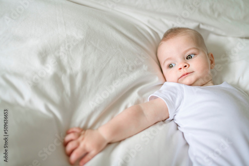 Adorable baby boy in white sunny bedroom in the morning at home