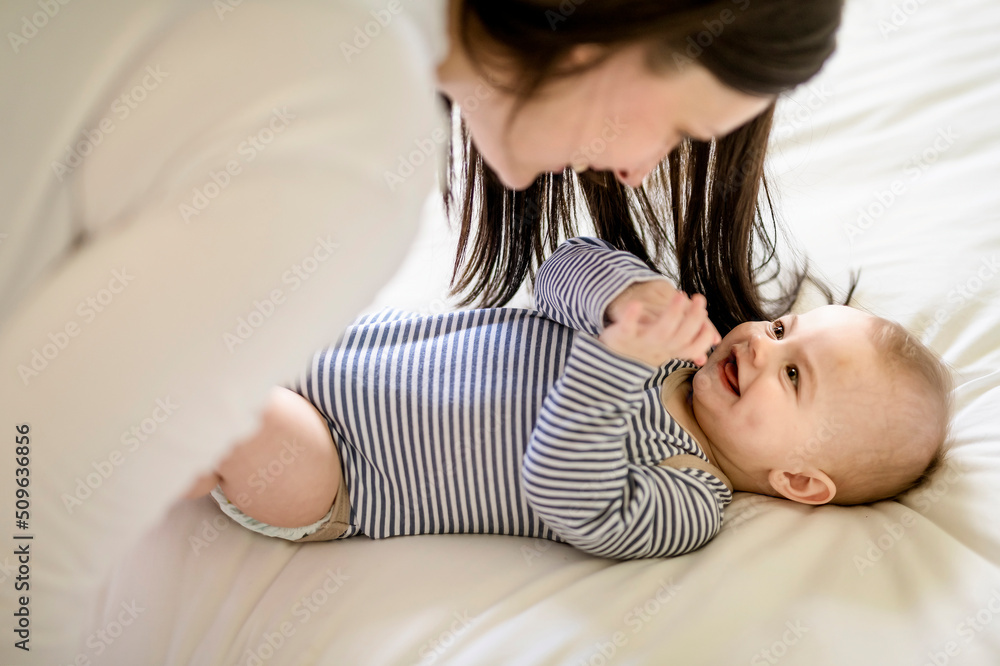 Mother and baby on white bed at home Mother and baby on white bed at home