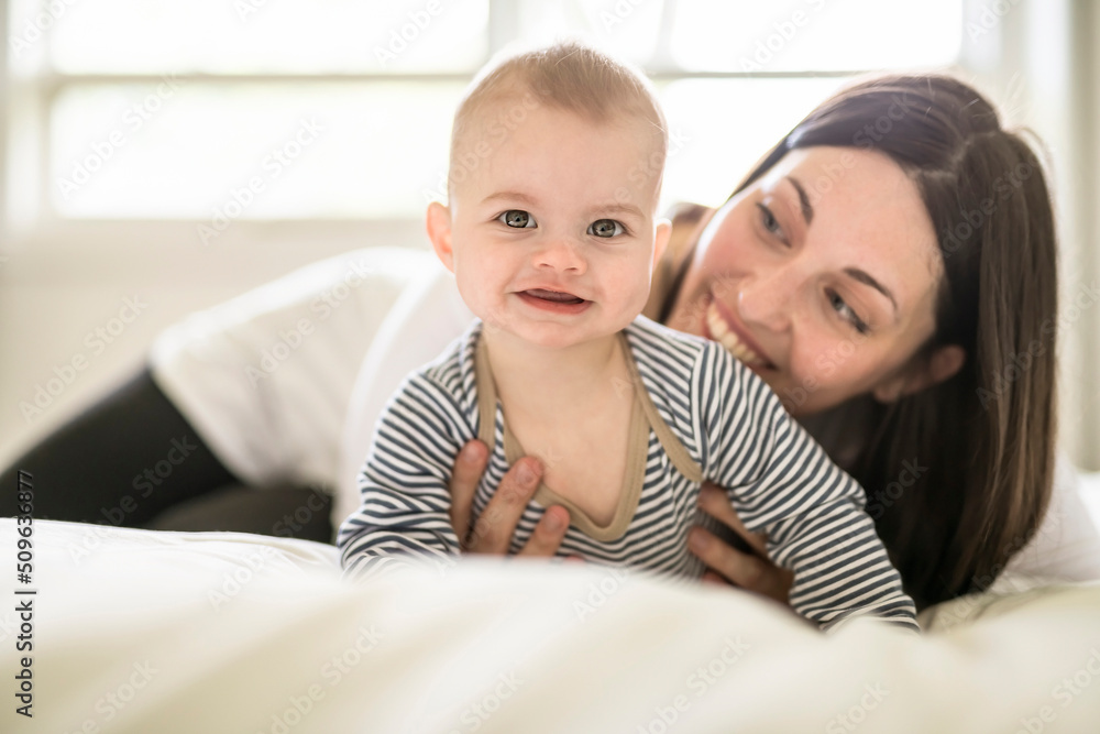Mother and baby on white bed at home Mother and baby on white bed at home