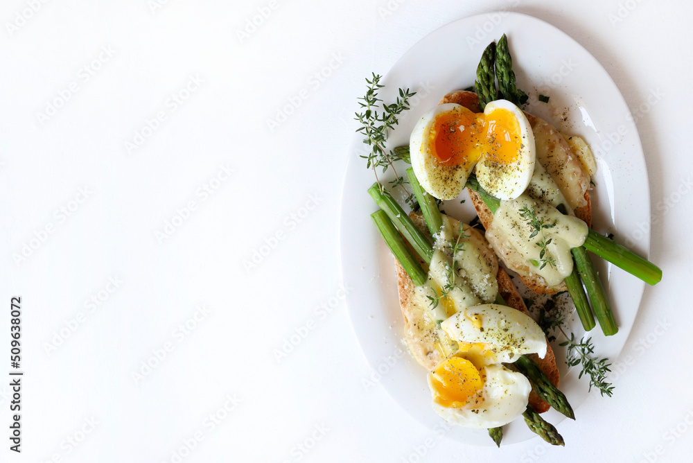 Bruschetta di asparagi, uova e formaggio su sfondo bianco. Direttamente sopra. Cibo salutare.