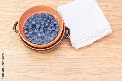 blueberries and water in a terracotta bowl on wooden table