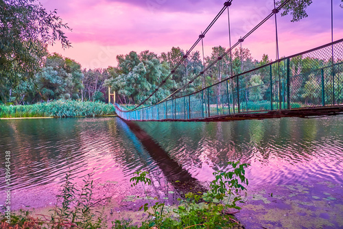 The dusk in Ukrainian village at old suspension bridge above Psel river, Velyka Bahachka, Ukraine photo