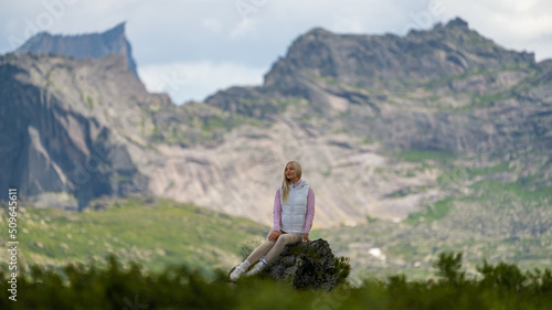 Portrait of a girl against the background of mountains. Summer day