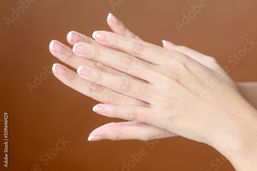 Close up young woman hand is applying cream over brown background   beauty skin care concept