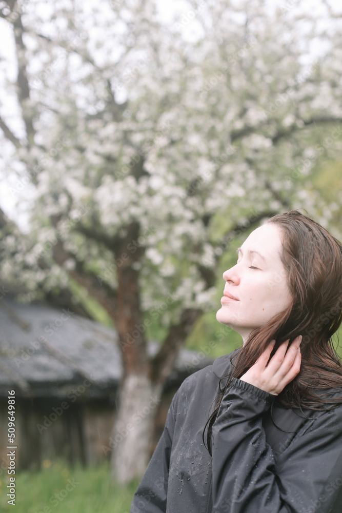 emotional portrait of a young woman standing alone under rain outdoors in spring. emotional portrait of a young woman standing alone under rain outdoors in spring.