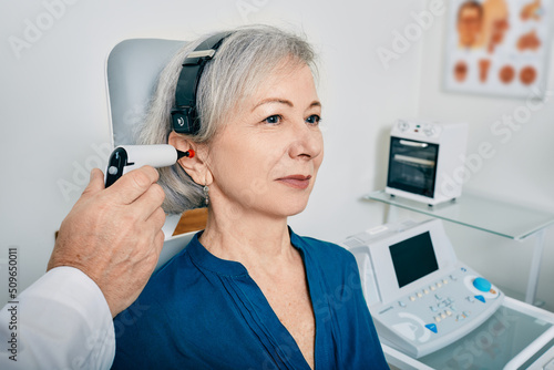 Elderly woman receives tympanometry with tympanometer probe at hearing clinic. Hearing check-up, impedance audiometry