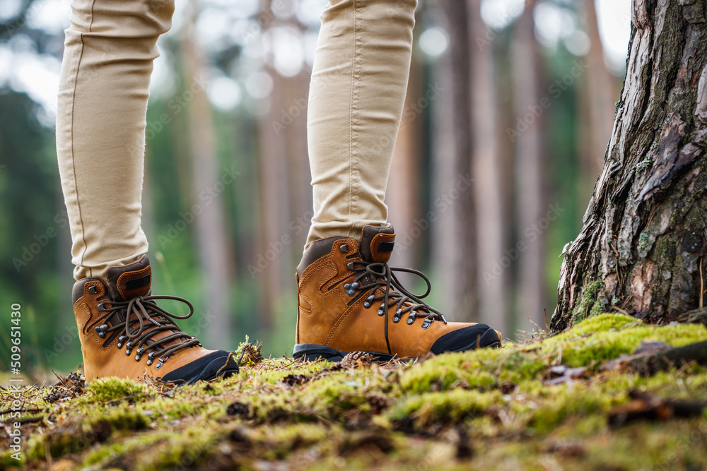 Tourist with hiking boots walking in forest. Brown leather ankle boot Tourist with hiking boots walking in forest. Brown leather ankle boot