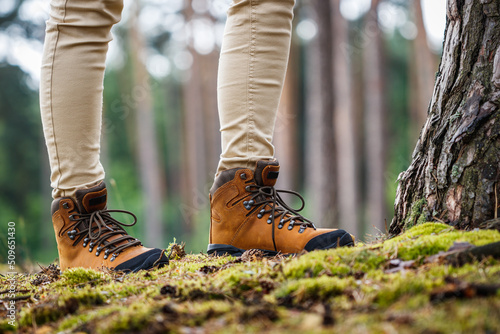 Tourist with hiking boots walking in forest. Brown leather ankle boot