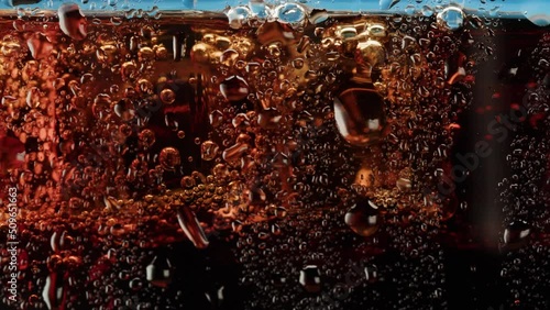 Cold lemonade in glass close-up. Coca cola with ice macro shooting texture. Refreshing cocktail.