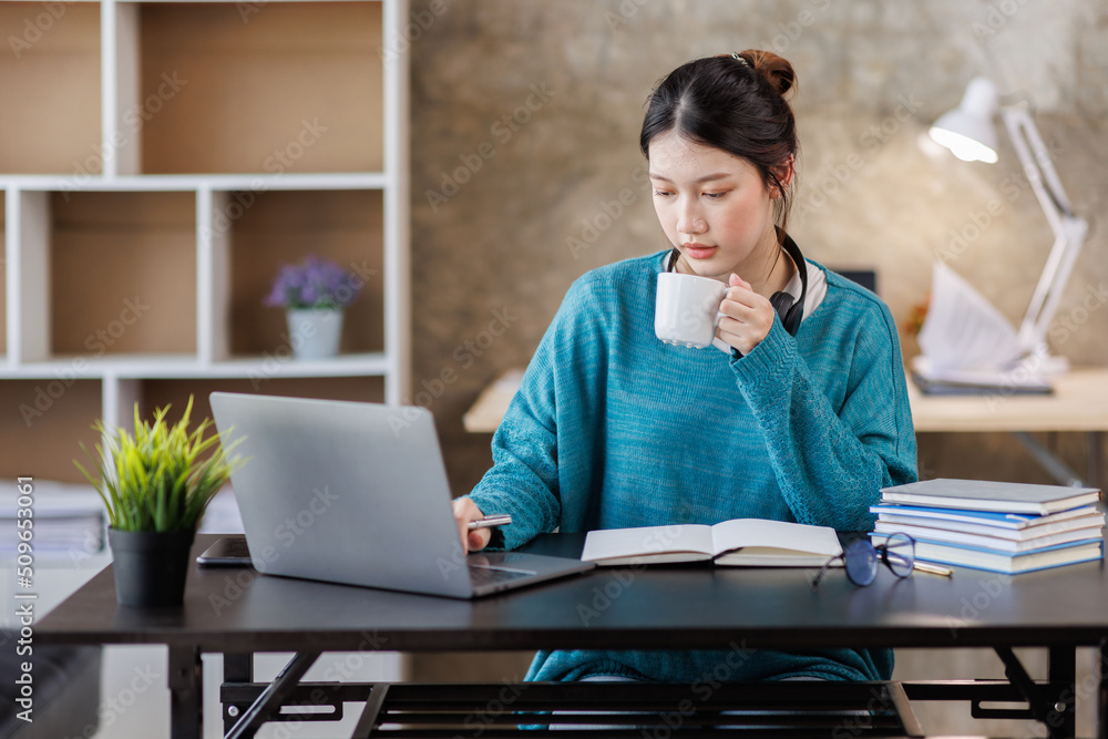 Young attractive female student writer scribing notes to a textbook to prepare for the Exam preparation, Asian girl sitting homework on a laptop computer, making a plan for tomorrow creating a list Young attractive female student writer scribing notes to a textbook to prepare for the Exam preparation, Asian girl sitting homework on a laptop computer, making a plan for tomorrow creating a list