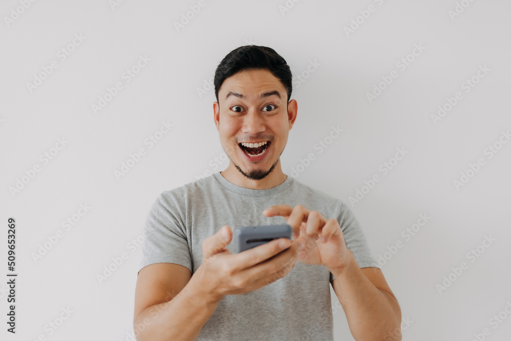 Wow and surprise face asian man use smartphone with copy space of advertisement. Wow and surprise face asian man use smartphone with copy space of advertisement.