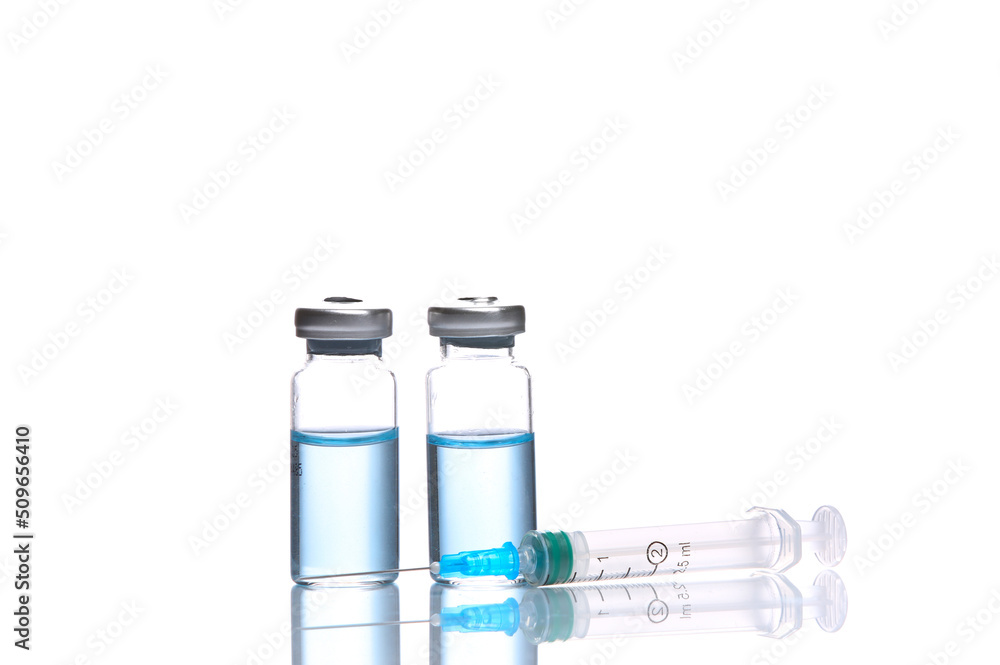 Vaccine bottles with blue liquid and syringe isolated on white background with reflection Vaccine bottles with blue liquid and syringe isolated on white background with reflection