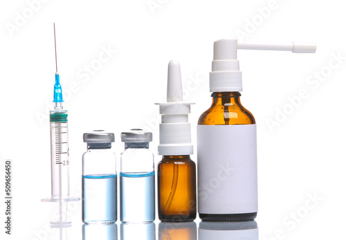 Medicines isolated on white background with reflection. Bottles of vaccine, throat spray and nasal spray with syringe photo