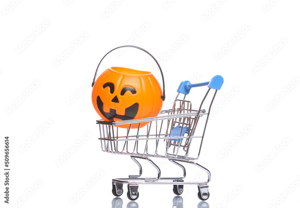 Mini shopping cart with halloween candy bucket isolated on white background with reflection