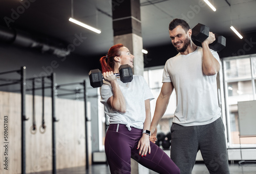 Smiling woman and man athlete with dumbbells in the gym. Healthy lifestyle