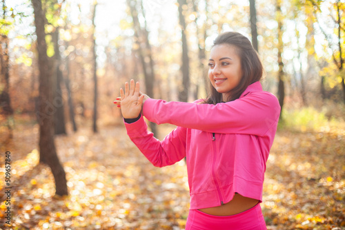 Outdoor workout. Young fitness woman in sportswear is training in the autumn forest. Healthy lifestyle