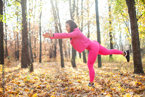 Outdoor workout. Young fitness woman in sportswear is training in the autumn forest. Healthy lifestyle