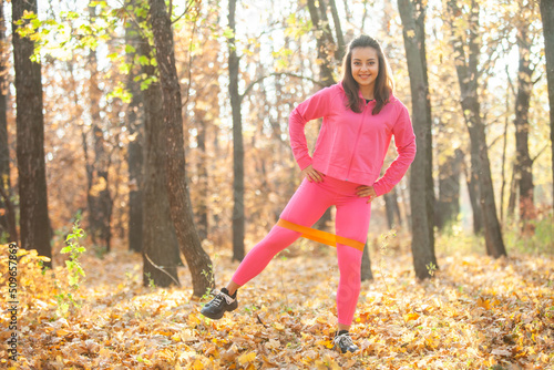 Active fit woman training with fitness band in autumn forest. Healthy lifestyle. Outdoor workout