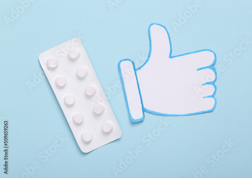 Blister of pills with thumb up icon on blue background