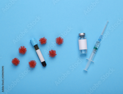 Testing and vaccination, covid 19 treatment. Vaccine bottle and blood test with blank label for brand, virus molecules and syringe on blue background. Top view. Flat lay
