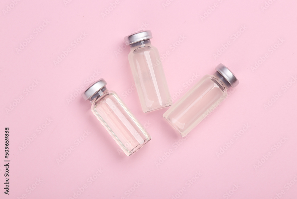 Naklejka premium Medical glass jars of vaccine on a pink background. Top view. Flat lay