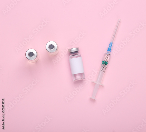 Vaccine bottle with a blank label for the brand and syringe on pink background. Covid 19 vaccination © splitov27