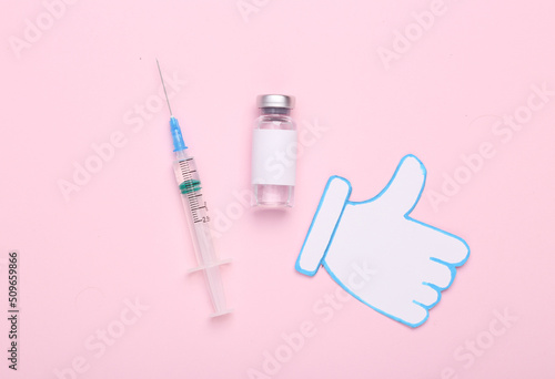 Approved vaccine. Vaccine bottle with blank label for the brand and syringe, thumbs up icon on pink background. Covid 19 pandemic, vaccination