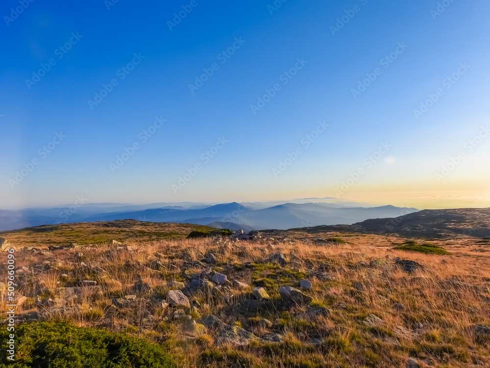 Mountain landscape at Torre, Serra da Estrela, Portugal. View of the golden vegetation field, mountain chain and widmills