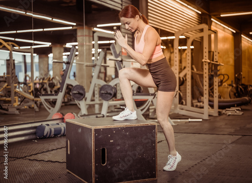 Fit woman in sportswear steps on wooden box in the gym. Intensive functional training © splitov27