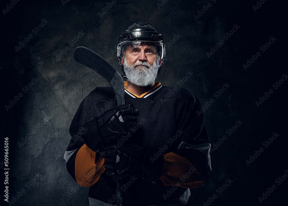 Shot of active senior man hockey player dressed in protective sportswear holding hockey stick. Shot of active senior man hockey player dressed in protective sportswear holding hockey stick.