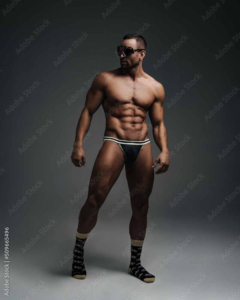 Fototapeta premium Naked sportsman in sunglasses standing in studio