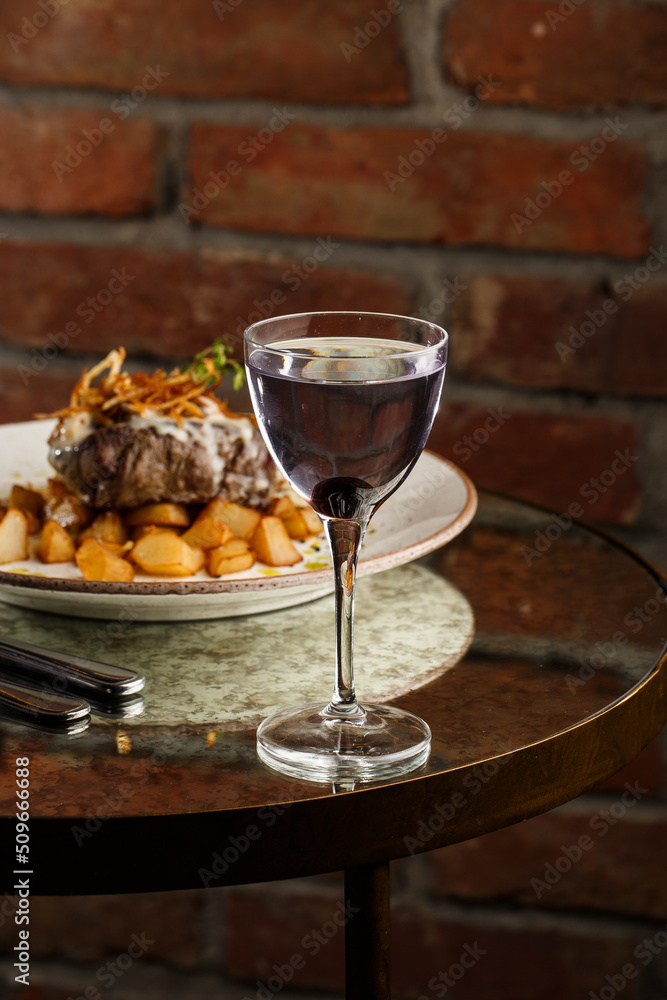 Grilled steak with baked golden potatoes served with crispy onion on top on a brick background. Delicious Recipe.