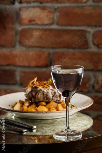 Grilled steak with baked golden potatoes served with crispy onion on top on a brick background. Delicious Recipe.