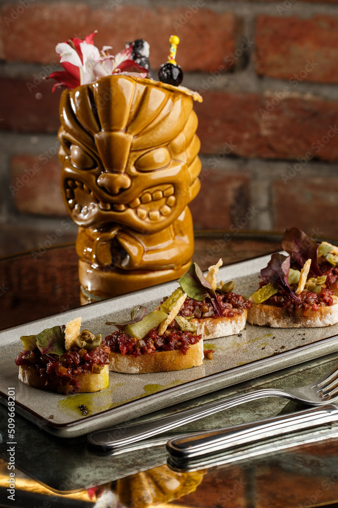 Four bruschettas with beef tartare on a plate, Crostini with Beef Tartare, beef Bruschetta, sandwich with raw gourmet beef.