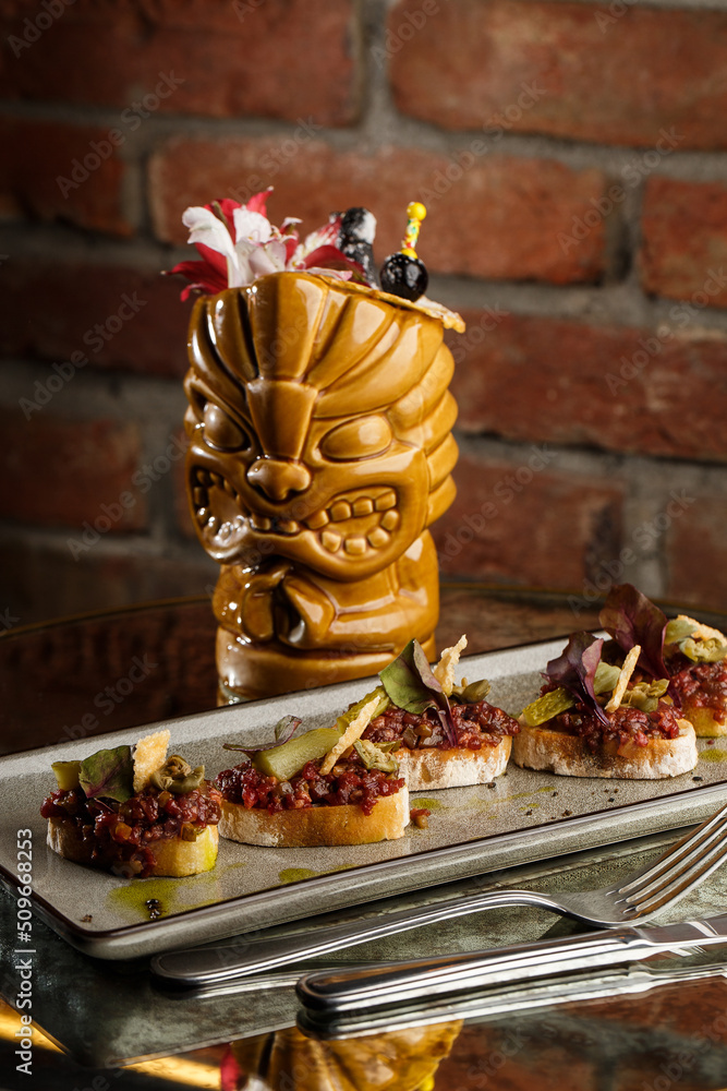 Four bruschettas with beef tartare on a plate, Crostini with Beef Tartare, beef Bruschetta, sandwich with raw gourmet beef.