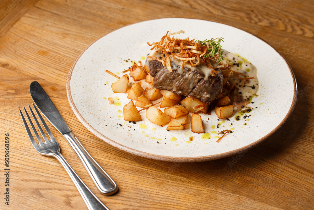 Grilled steak with baked golden potatoes served with crispy onion on top on a brick background. Delicious Recipe.