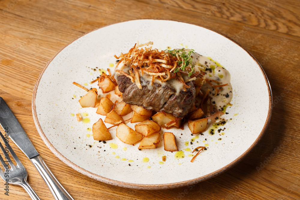 Grilled steak with baked golden potatoes served with crispy onion on top on a brick background. Delicious Recipe.