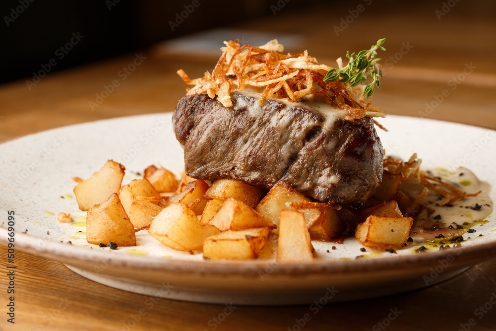 Grilled steak with baked golden potatoes served with crispy onion on top on a brick background. Delicious Recipe.