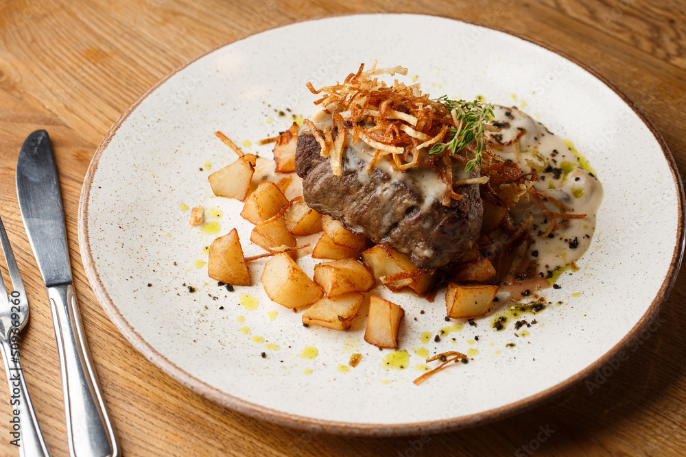 Grilled steak with baked golden potatoes served with crispy onion on top on a brick background. Delicious Recipe.