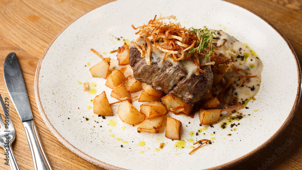Grilled steak with baked golden potatoes served with crispy onion on top on a brick background. Delicious Recipe.