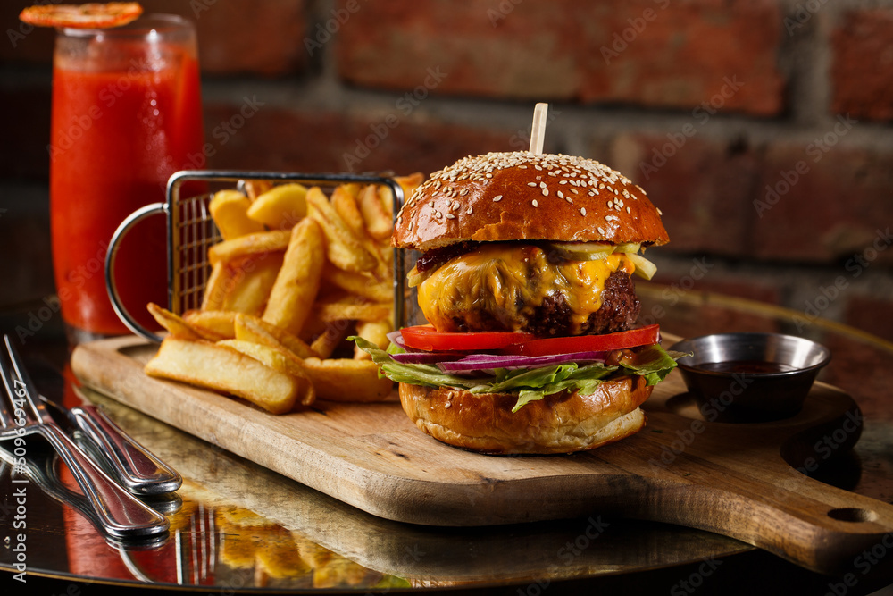 Big cheeseburger with french fries isolated on white background. Hamburger with beef patty onion, tomato, lettuce pickles, melted cheddar, mustards, tomato jam, mayo
