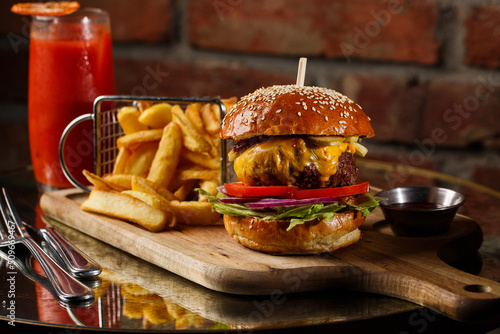 Obraz na płótnie Big cheeseburger with french fries isolated on white background. Hamburger with beef patty onion, tomato, lettuce pickles, melted cheddar, mustards, tomato jam, mayo w salonie