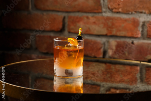 Obraz na płótnie Crystal glass with bright cold alcoholic cocktail decorated with orange zest. Blurred background. Negroni cocktail. w salonie