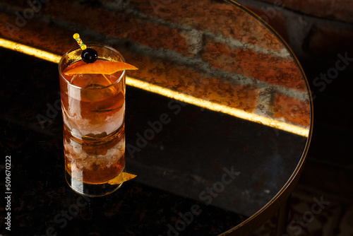 Obraz na płótnie Crystal glass with bright cold alcoholic cocktail decorated with orange zest. Blurred background. Negroni cocktail. w salonie