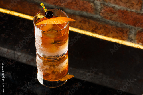 Obraz na płótnie Crystal glass with bright cold alcoholic cocktail decorated with orange zest. Blurred background. Negroni cocktail. w salonie