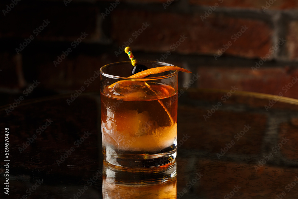 Crystal glass with bright cold alcoholic cocktail decorated with orange zest. Blurred background. Negroni cocktail.